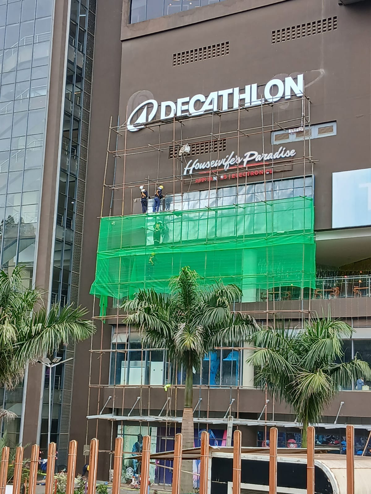 Facade scaffolding with debris netting and crew at Two Rivers Mall